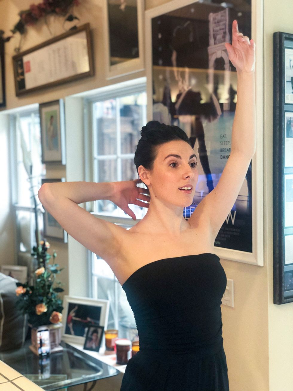 Peck stands with one arm in fifth position and demonstrates elongating the back of her neck with the other.