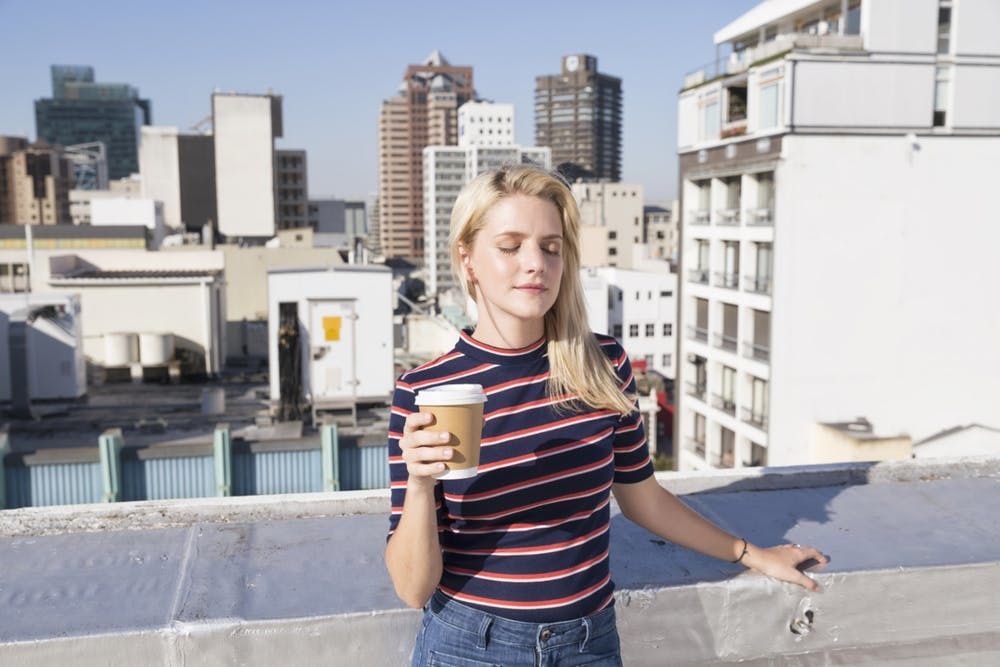 Une femme prend une tasse de café sur un toit