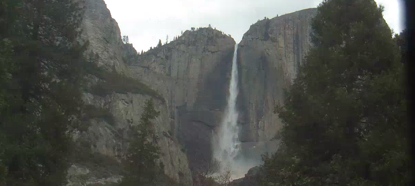 een foto van een live webcam weergave van Yosemite Falls in Californië, met pijnbomen die de 6500-voet falls omlijsten.
