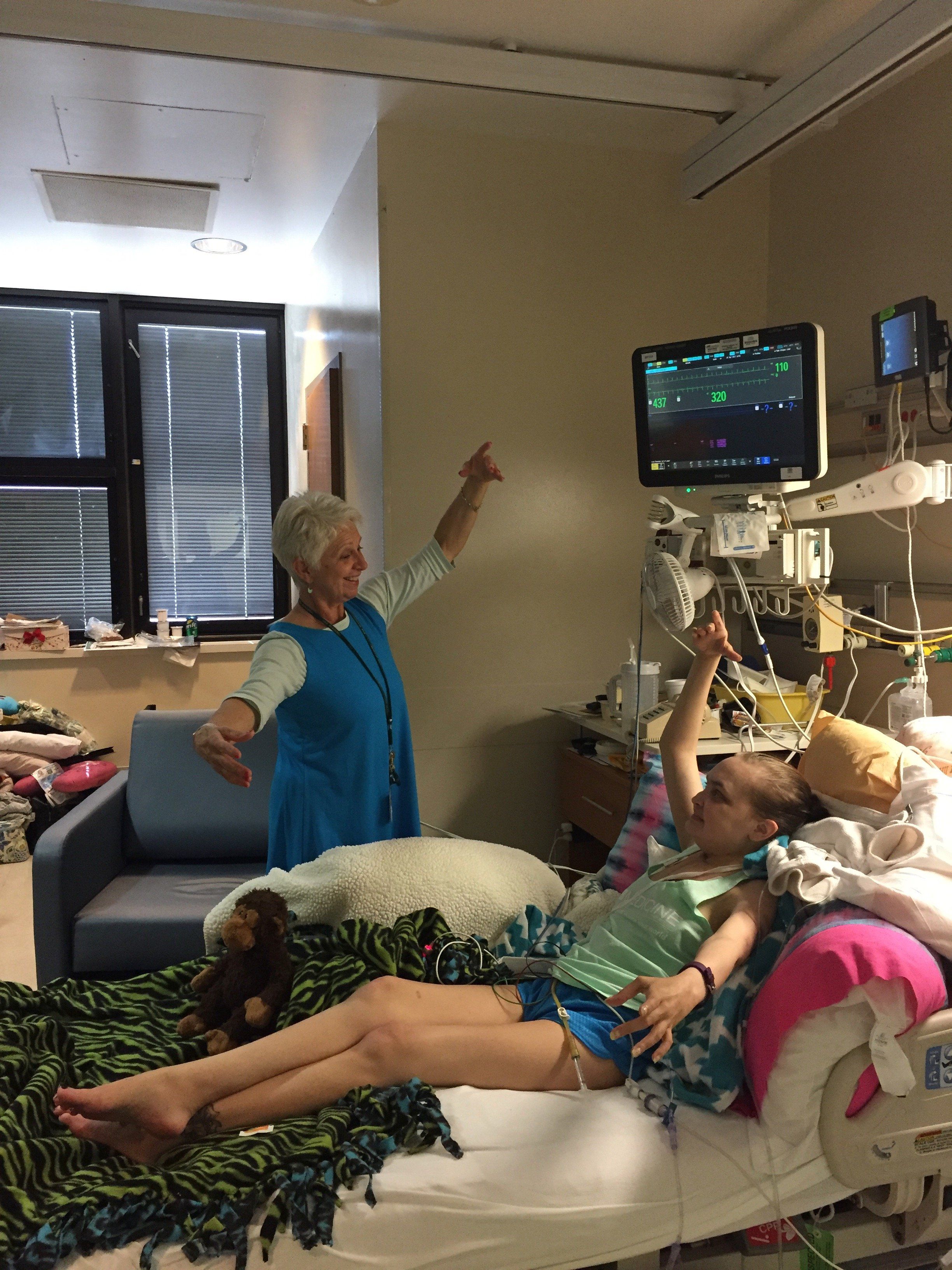 Turnage demonstrates a port de bras and is copied by a young girl in her hospital bed.