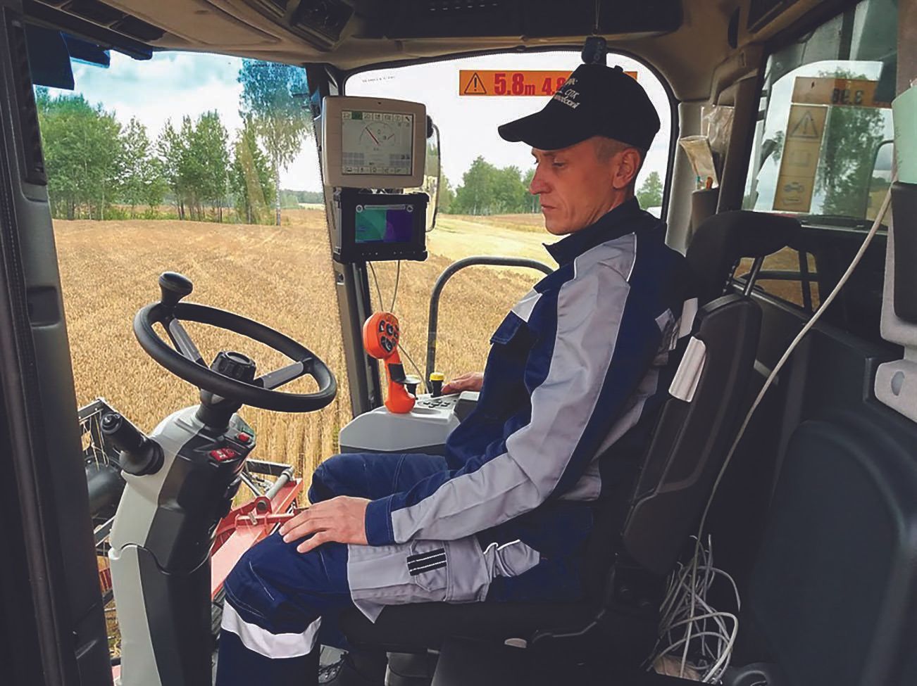 Image of a operator within a combine harvester, operating equipment.