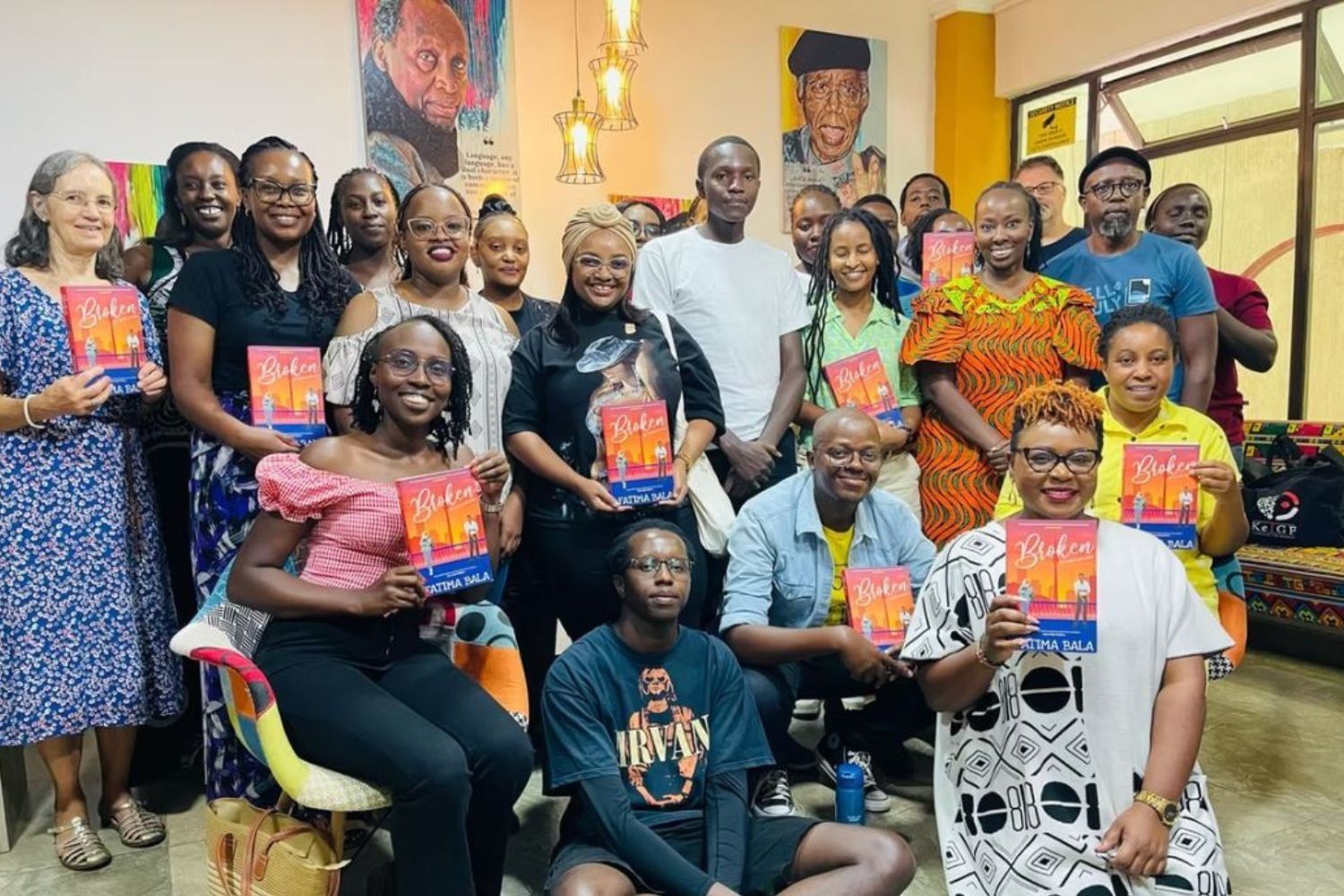 A smiling group of people gathered around holding copies of a book.