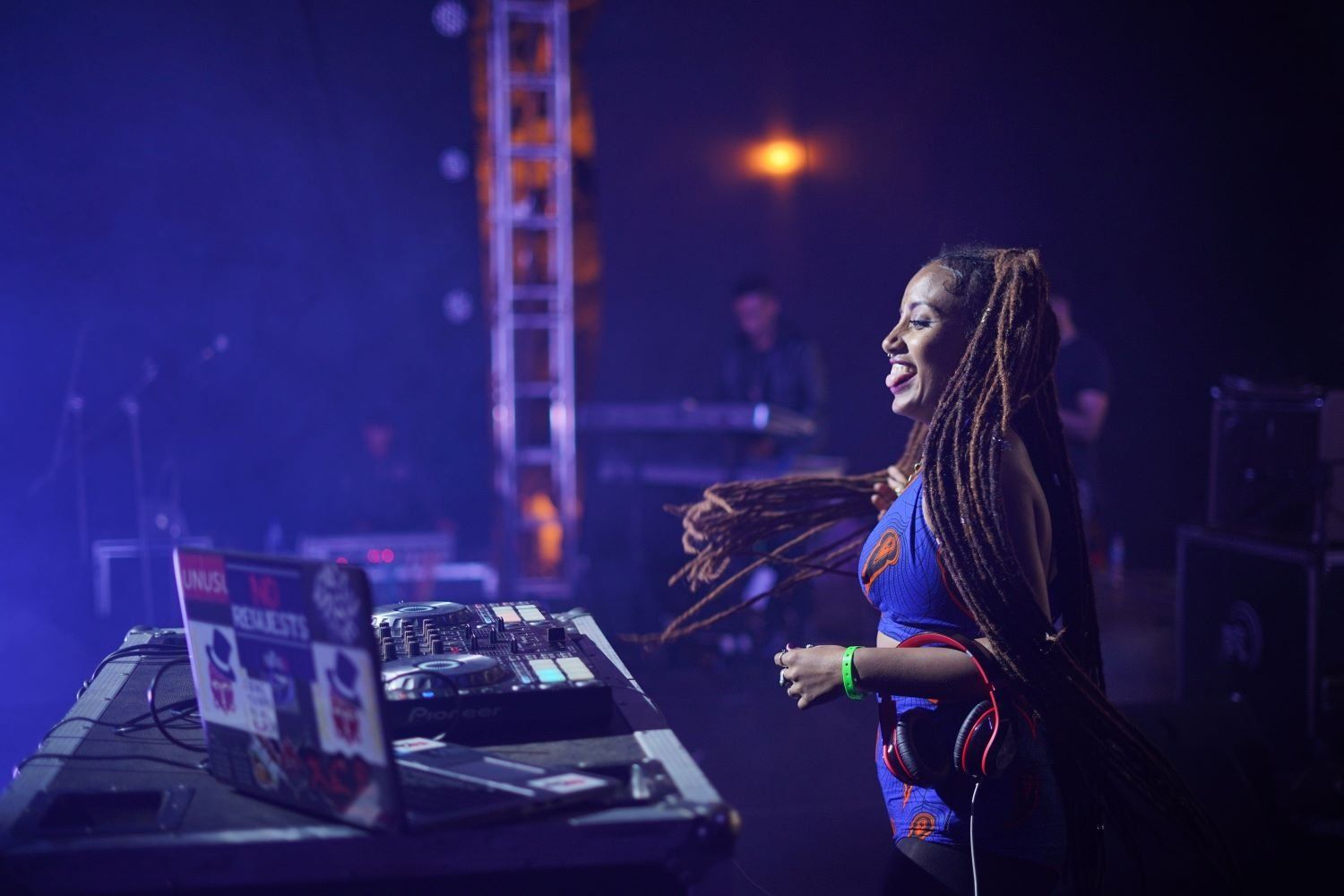 Lady Hash performs at a DJ booth surrounded by blue stage lighting.