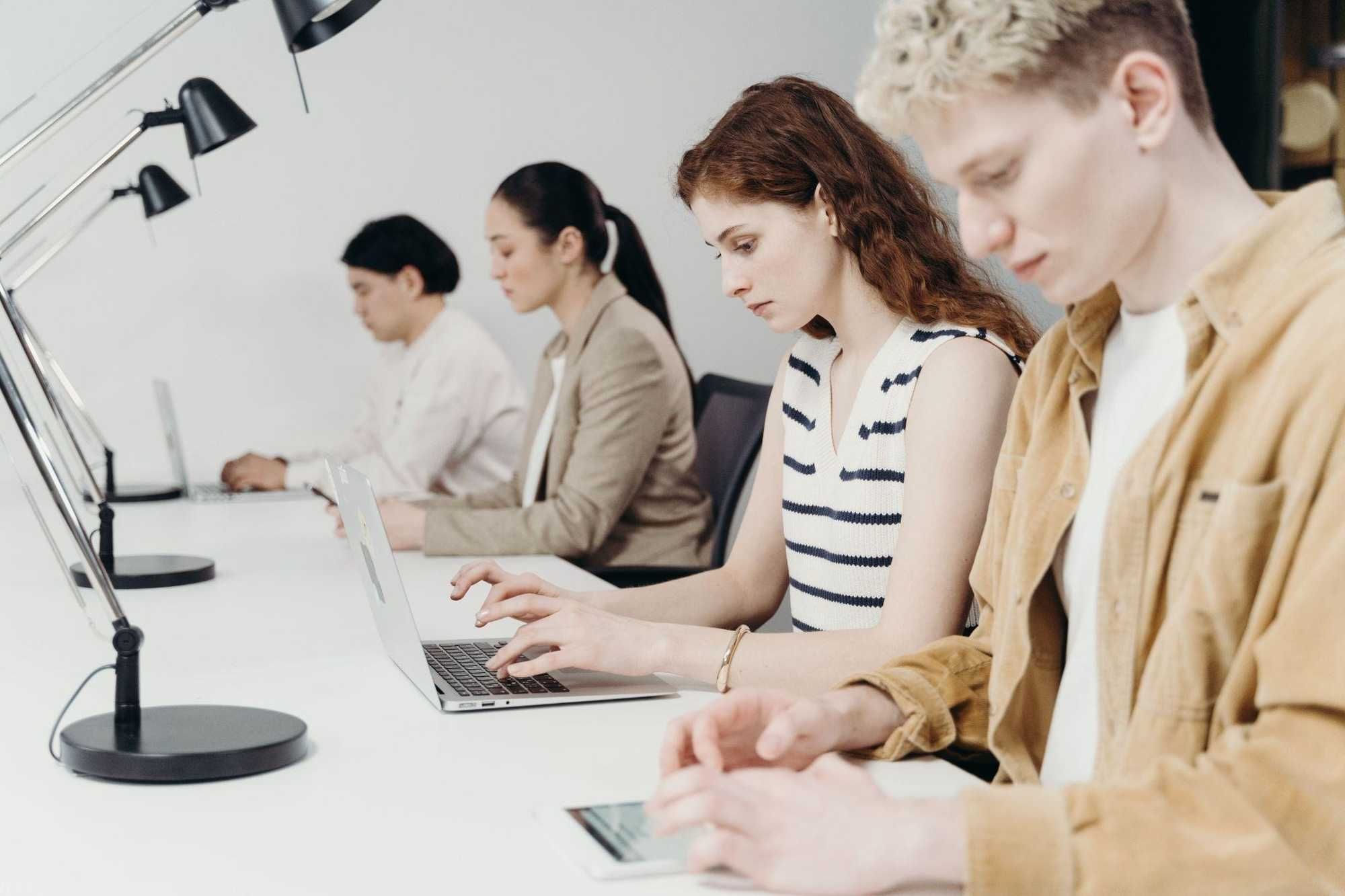 Diverse group of professionals working on laptops at a bright office workstation