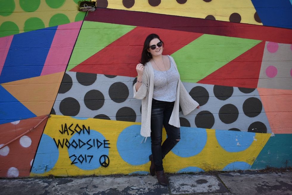 young college woman standing next to painted urban art wall mural
