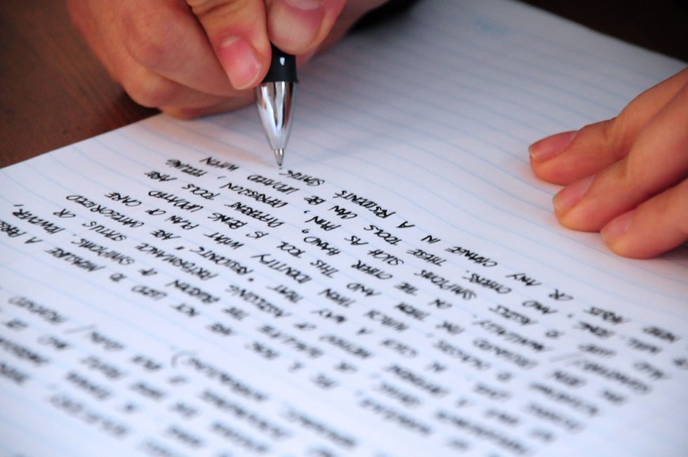 writing on a page with a hand holding a pen as if the person is beginning to write something