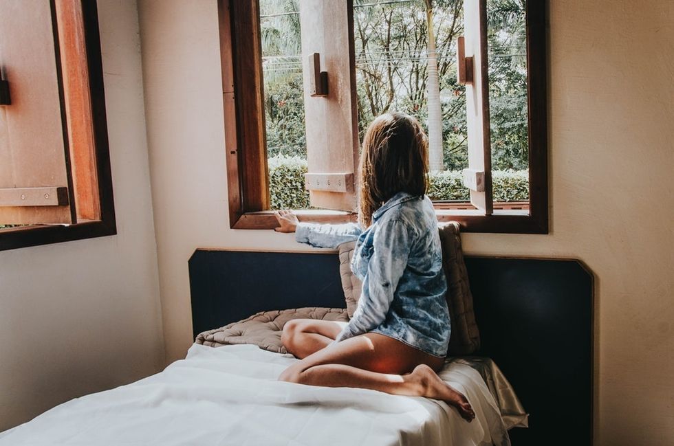 woman sitting in bed looking out window