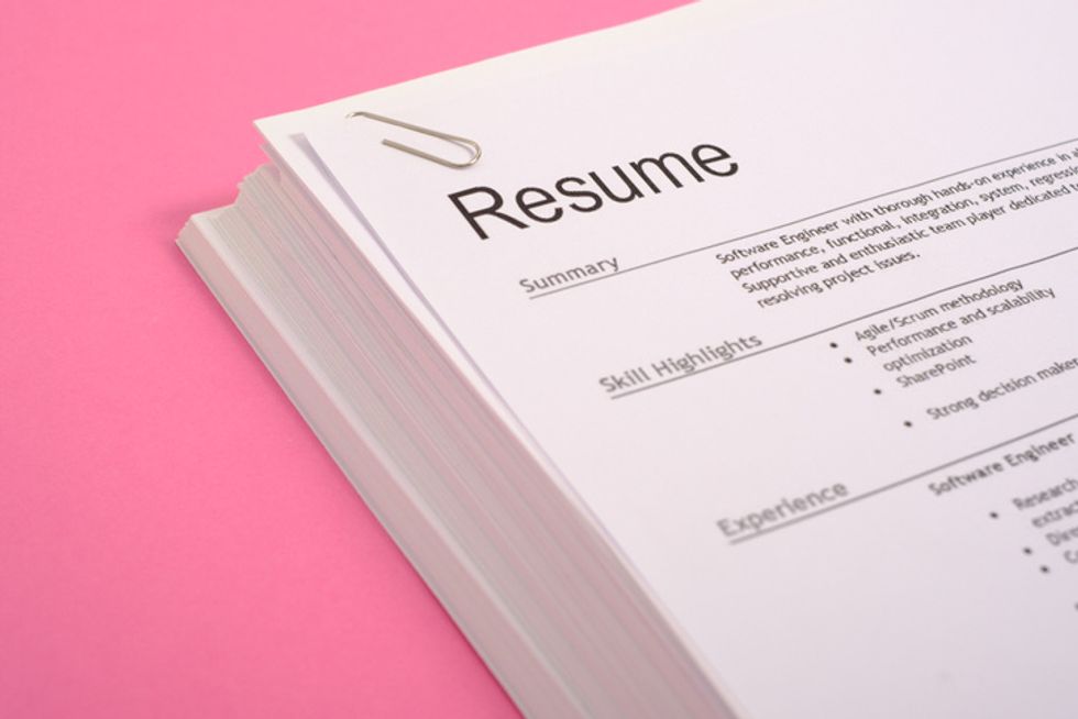 a pink background with a stack of resumes pictured