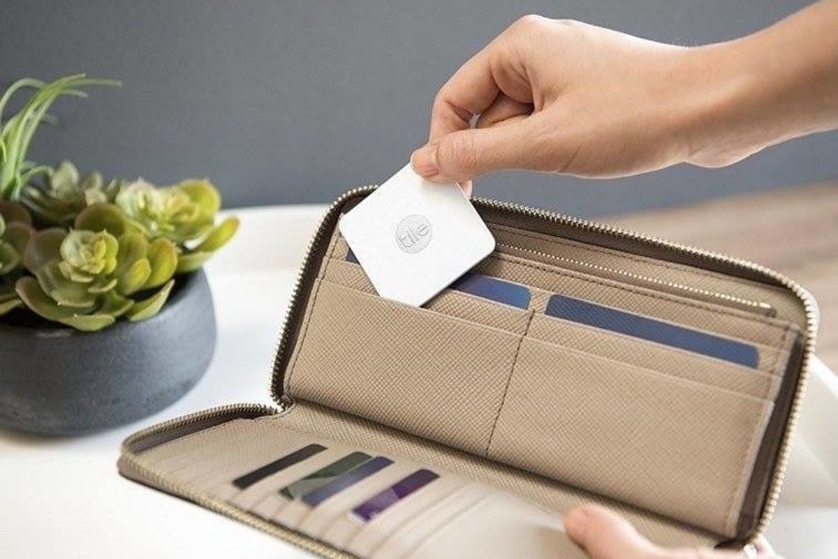 a photo of a person placing Tile tracker in a wallet