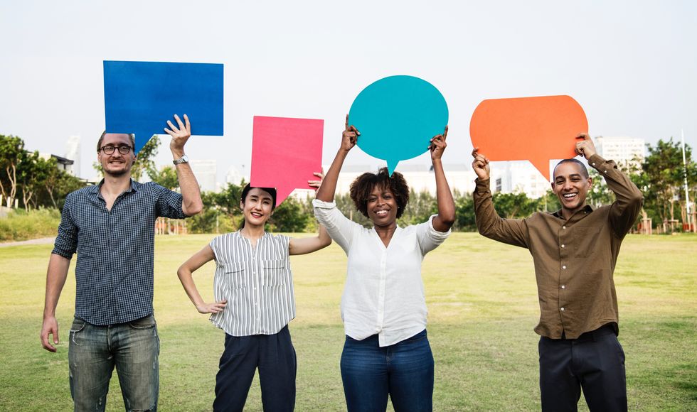 people holding speech bubbles while standing on grass field