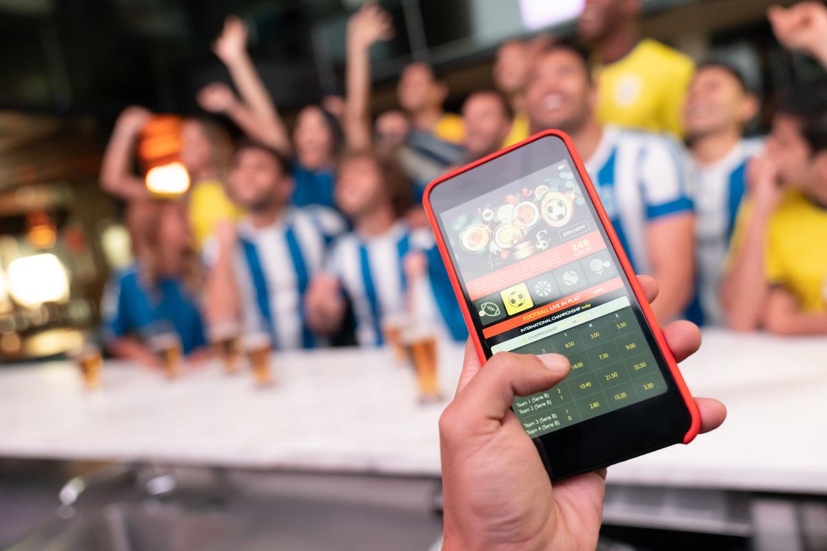 man holds cellphone with sports app