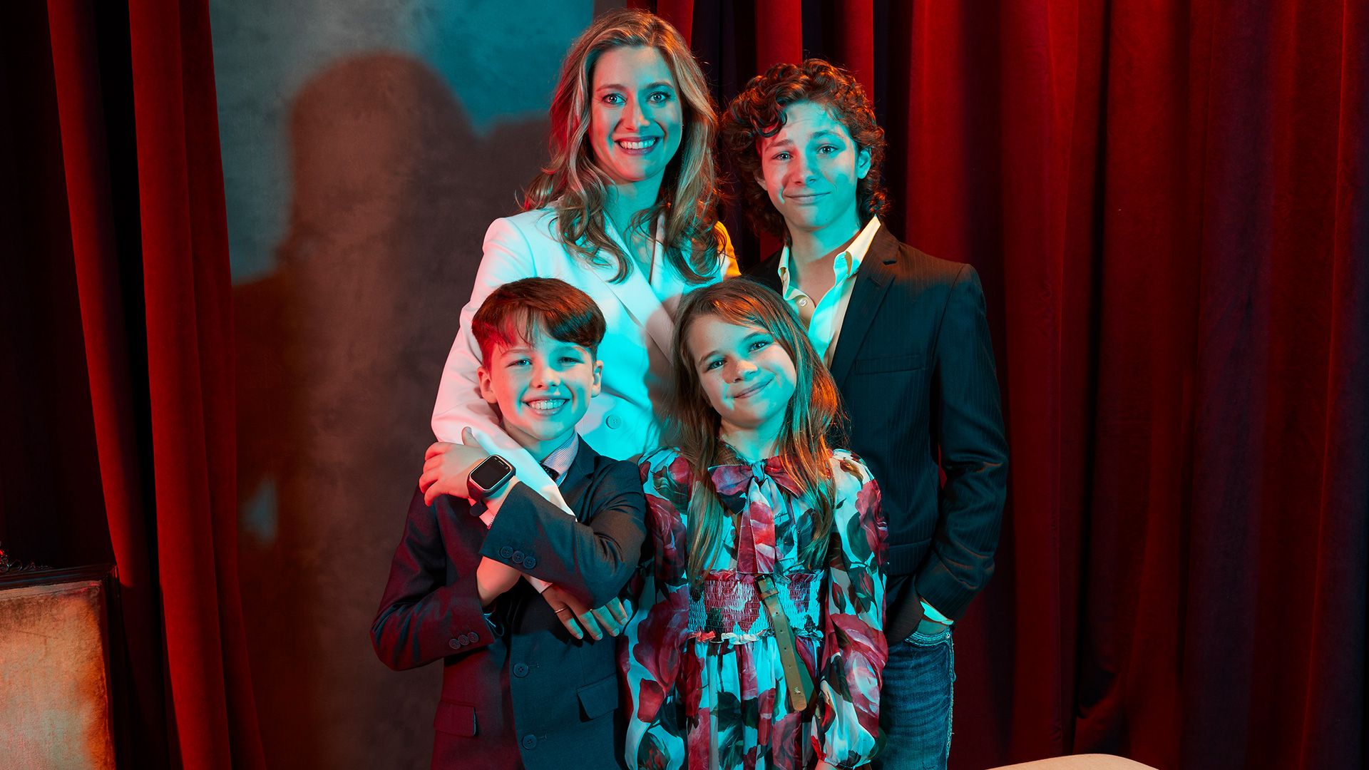 The cast of Young Sheldon stands in front of a red velvet curtain.