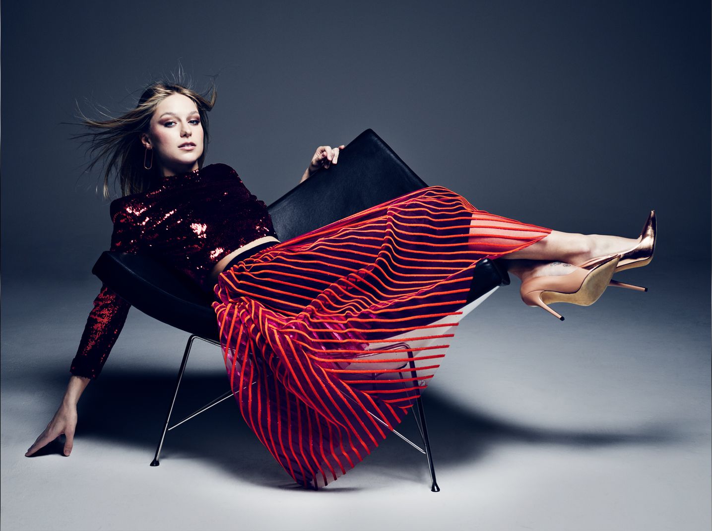 Supergirl Star Melissa Benoist wears a deep red sequined top and a transluscent striped red skirt.