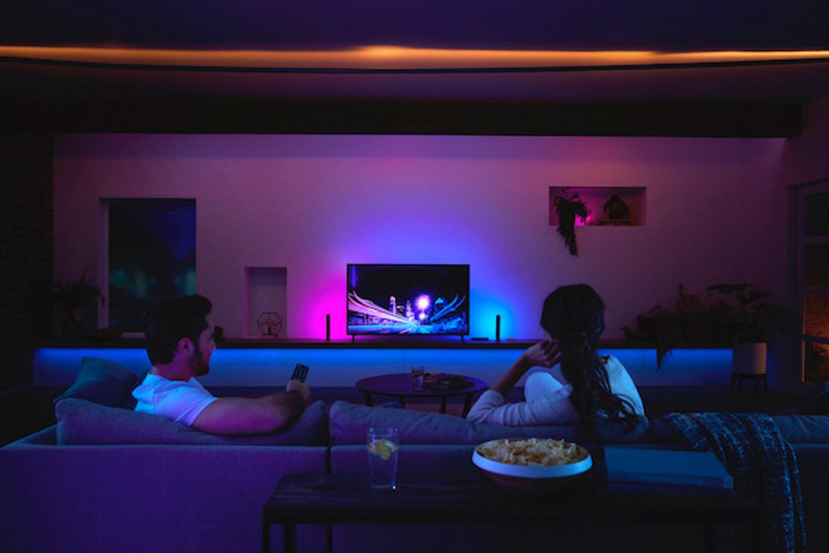 Two people on a couch watching TV with purple and pink lights glowing