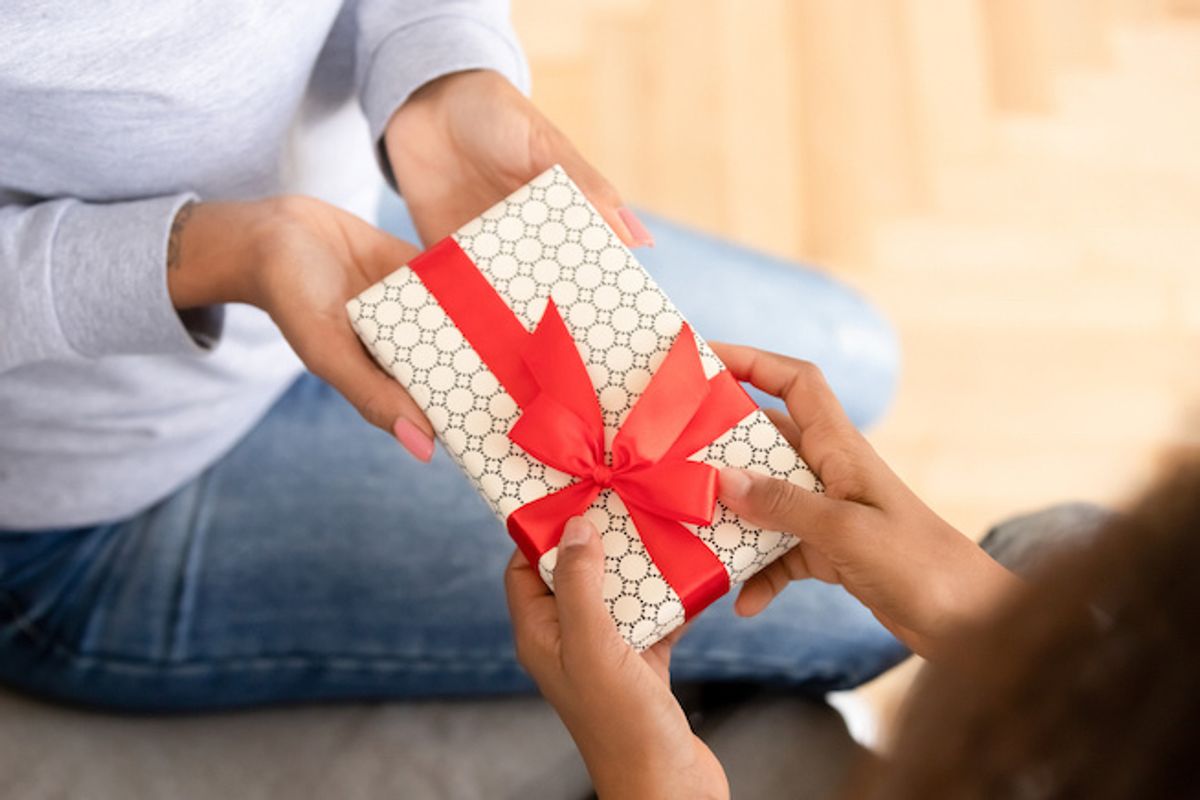 One person handing another person a beautifully wrapped gift with a red bow