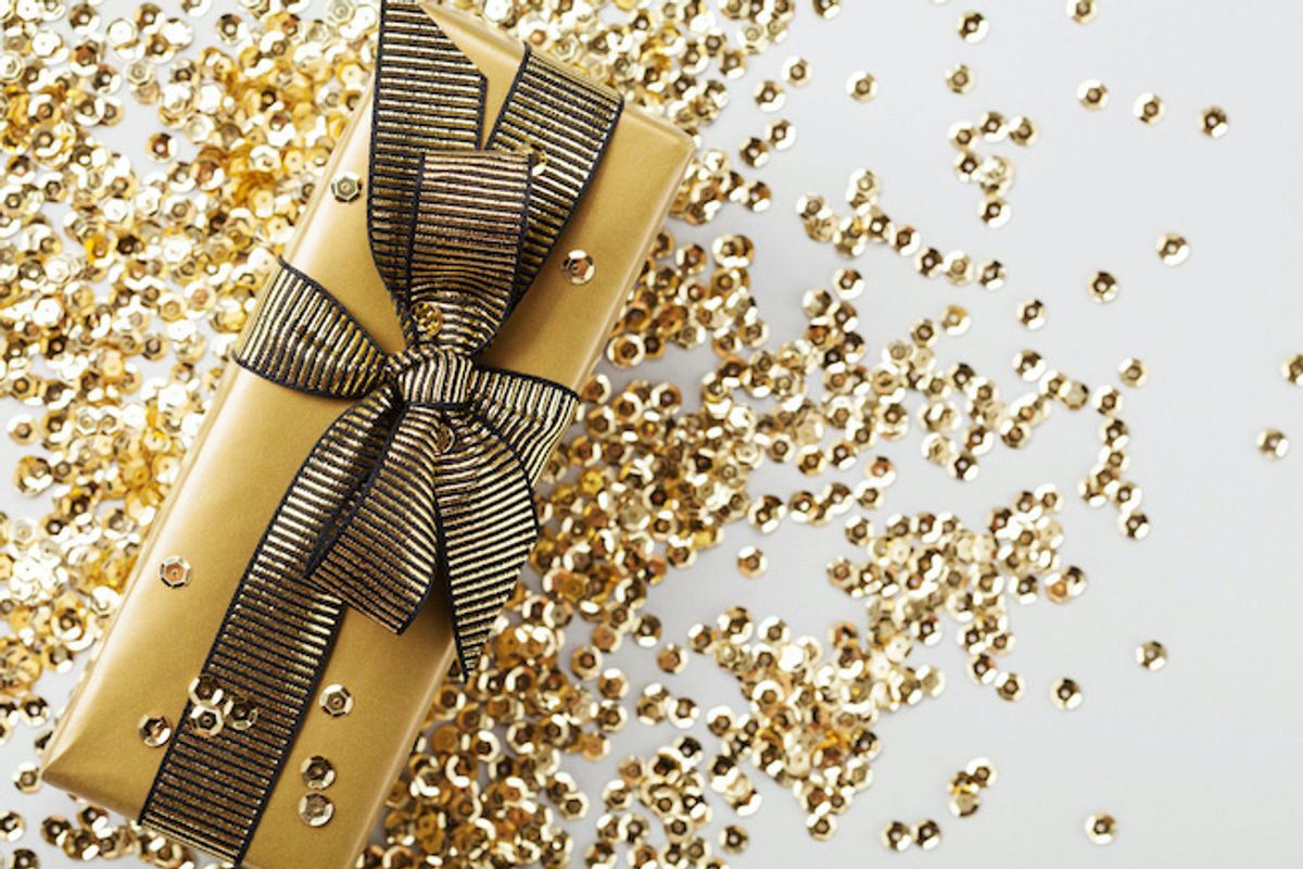 A present wrapped in gold paper with a gold ribbon, and gold sequins 