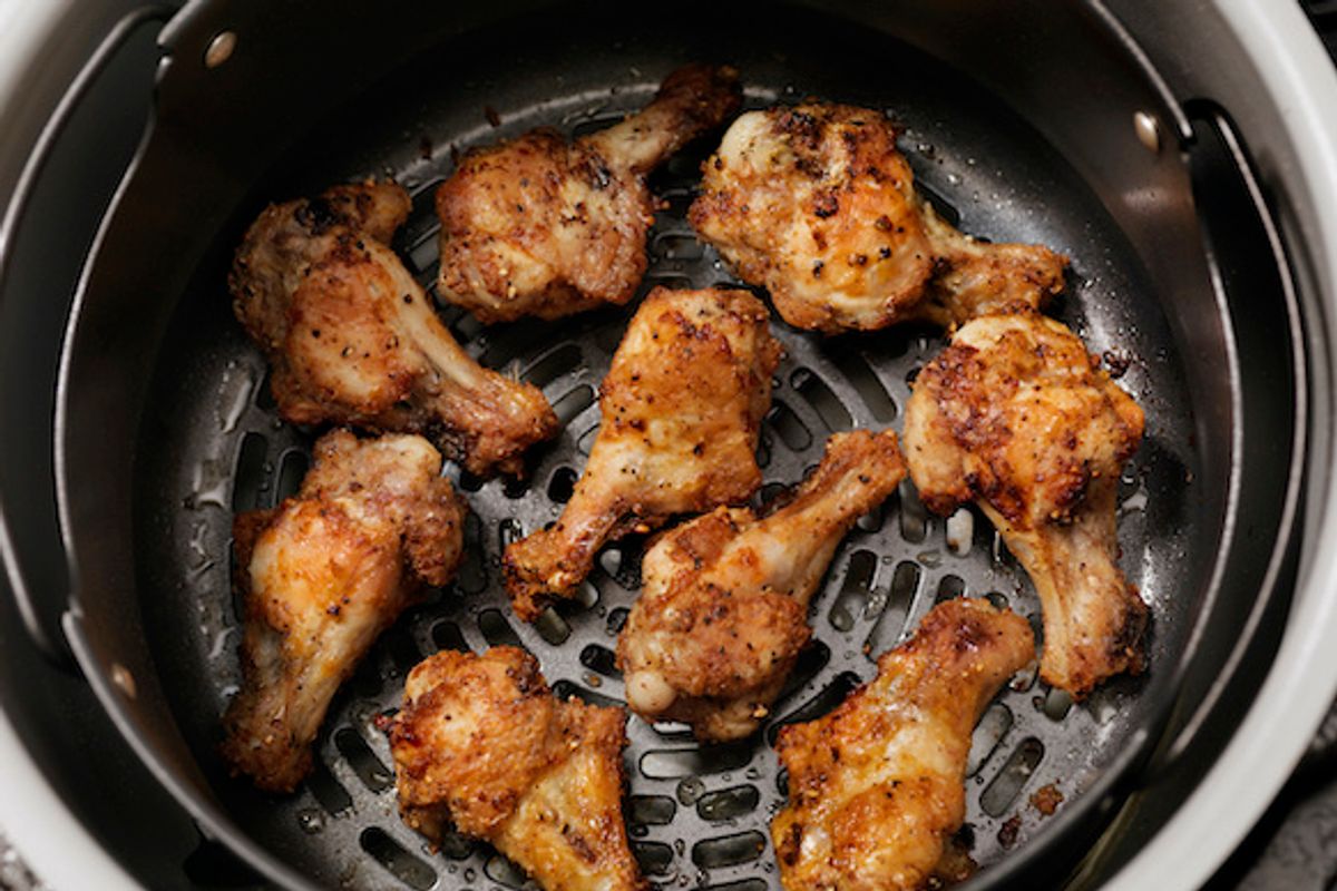 An air fryer with chicken wings cooked inside