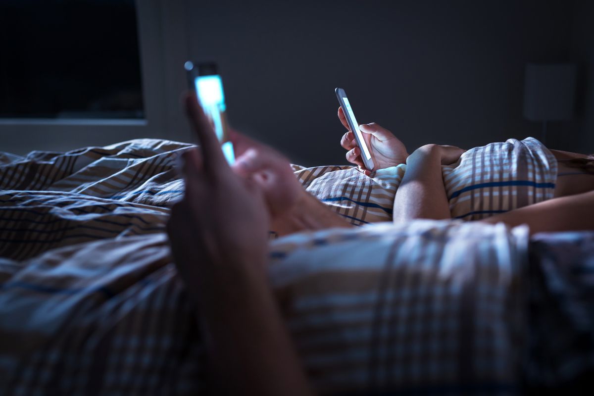 Couple using smartphones in bed