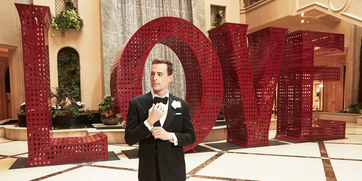Sean Murray in a tux standing in front of a LOVE art installation.
