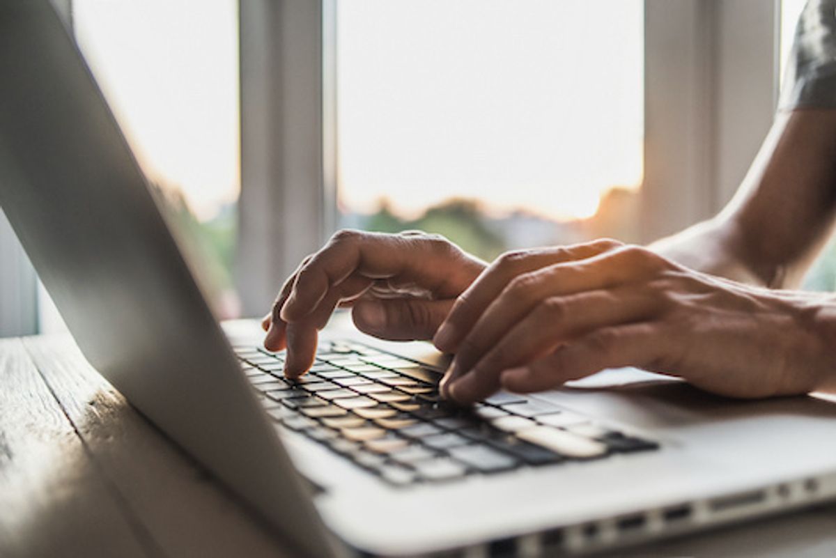 Hands typing on a laptop