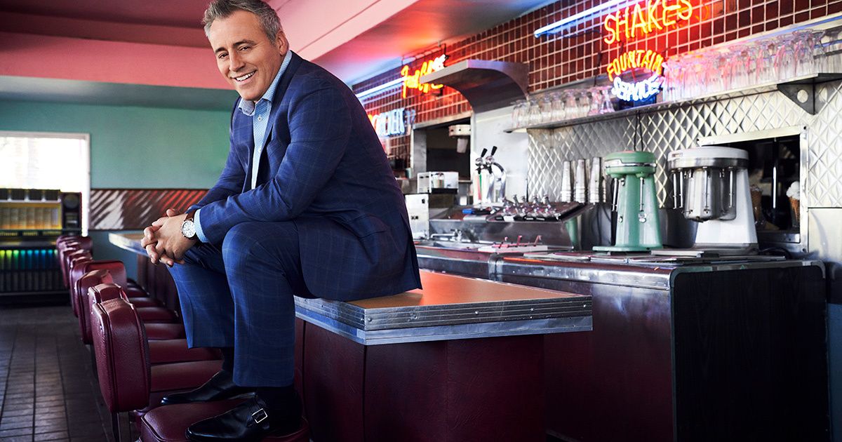Matt LeBlanc in a vintage diner sitting on the counter with his feet on the seat.