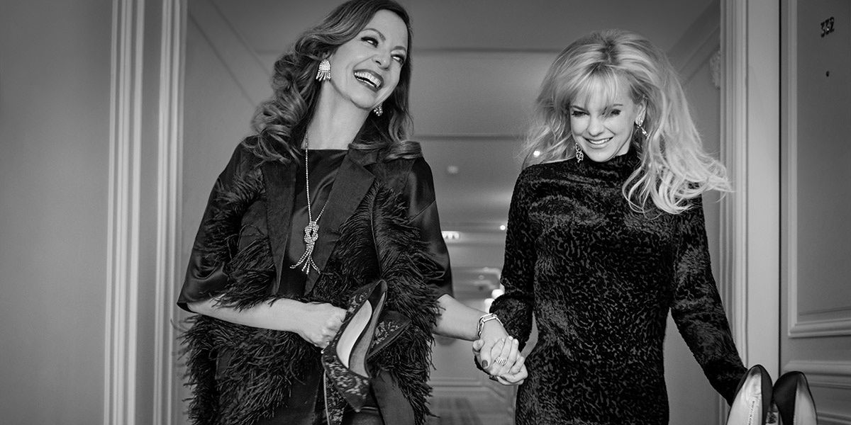 Black and white photo Allison Janney and Anna Faris holding hands.