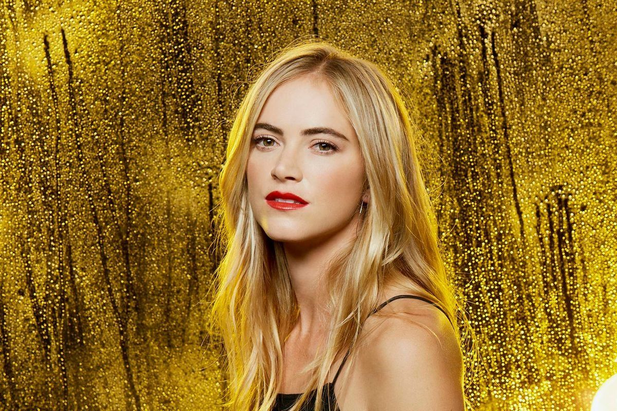 Emily Wickersham with a bold red lip against a rainy yellow backdrop.