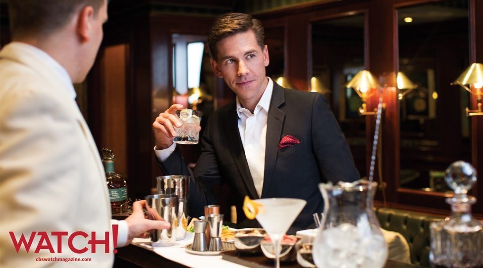 Brian Dietzen standing at a bar with a drink in his hand