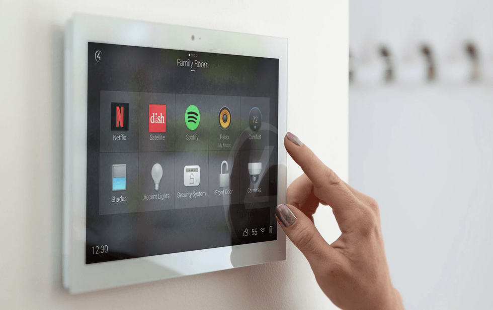 a photo of Control4's hub on a wall with a person activating home security
