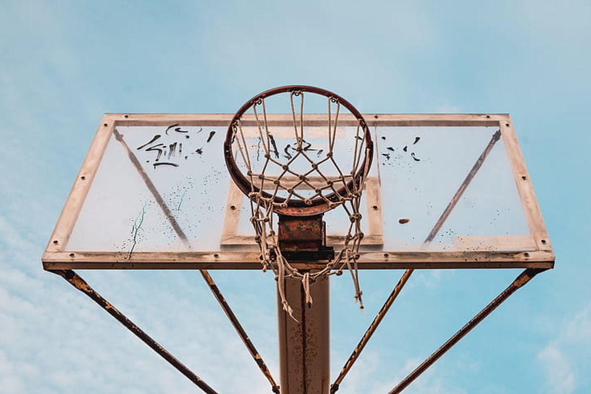 A dirty, beat-up basketball hoop sits unused. 