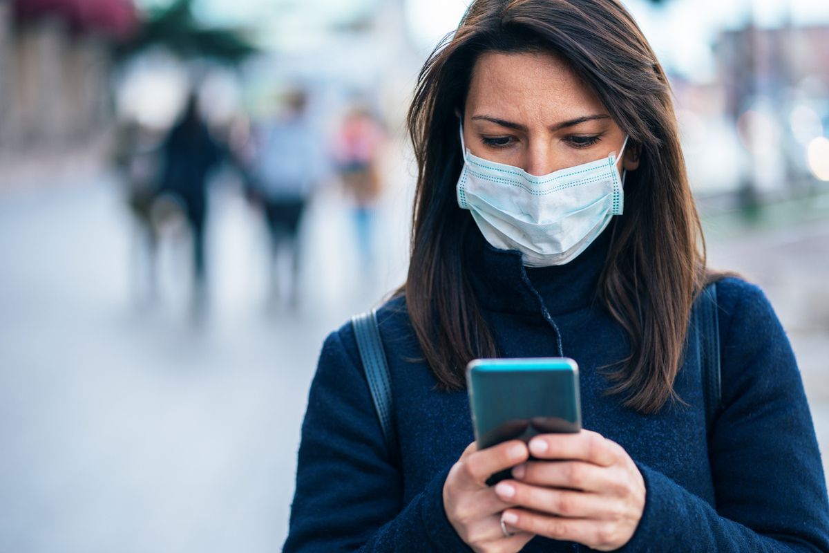 Woman wearing a mask holding a smartphone