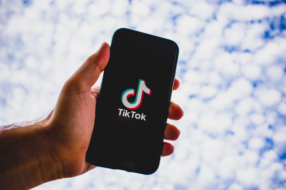 Person holding Iphone with the TikTok logo on screen.