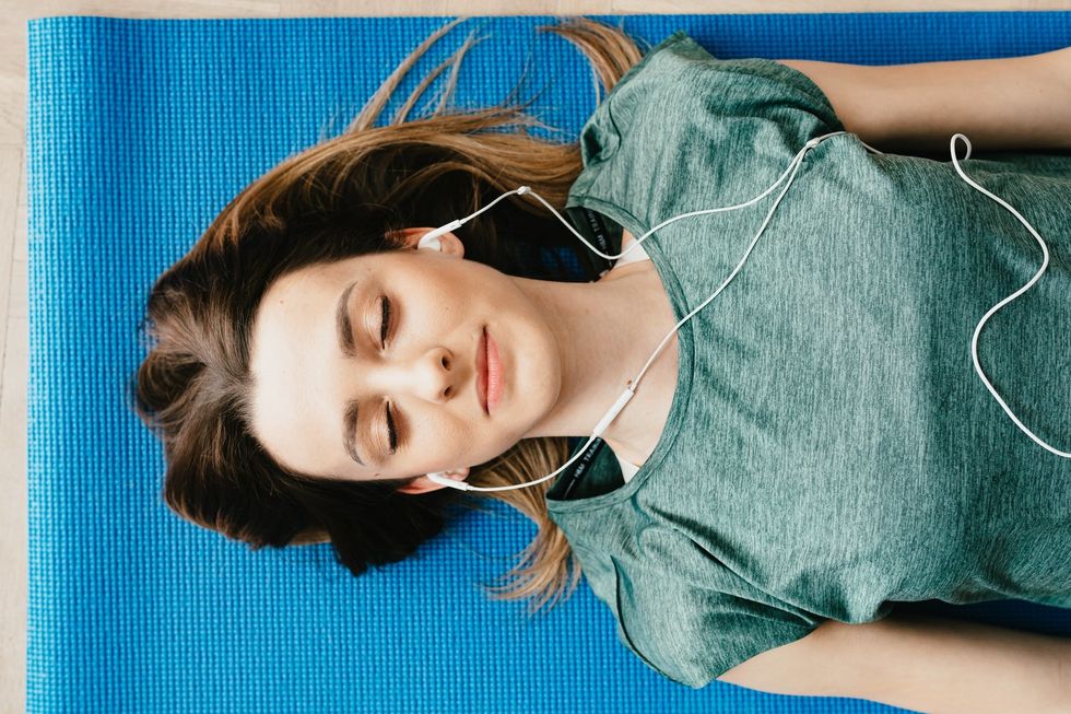 Woman listening to music laying down on yoga mat