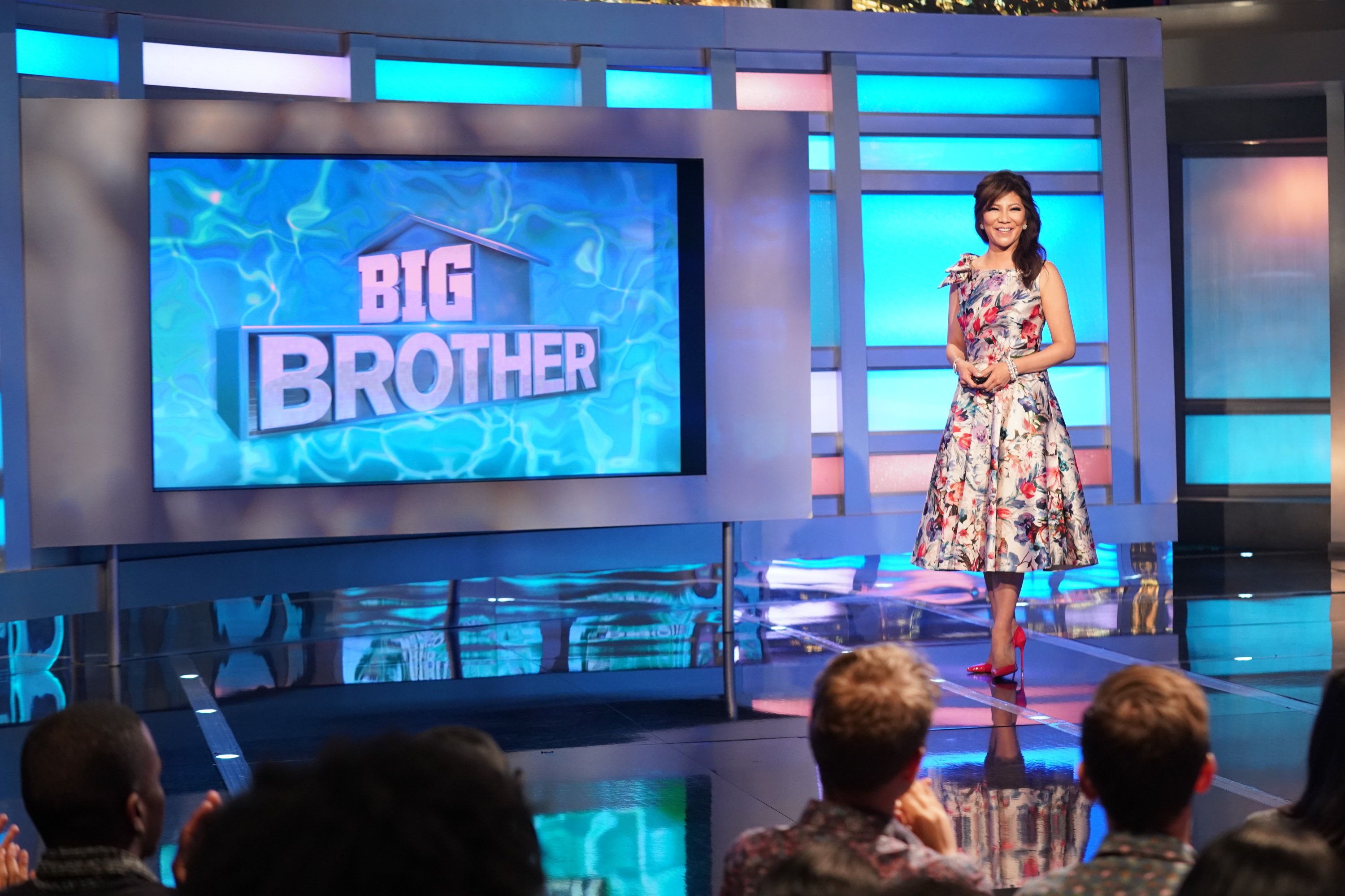Host Julie Chen standing in front of a Big Brother screen