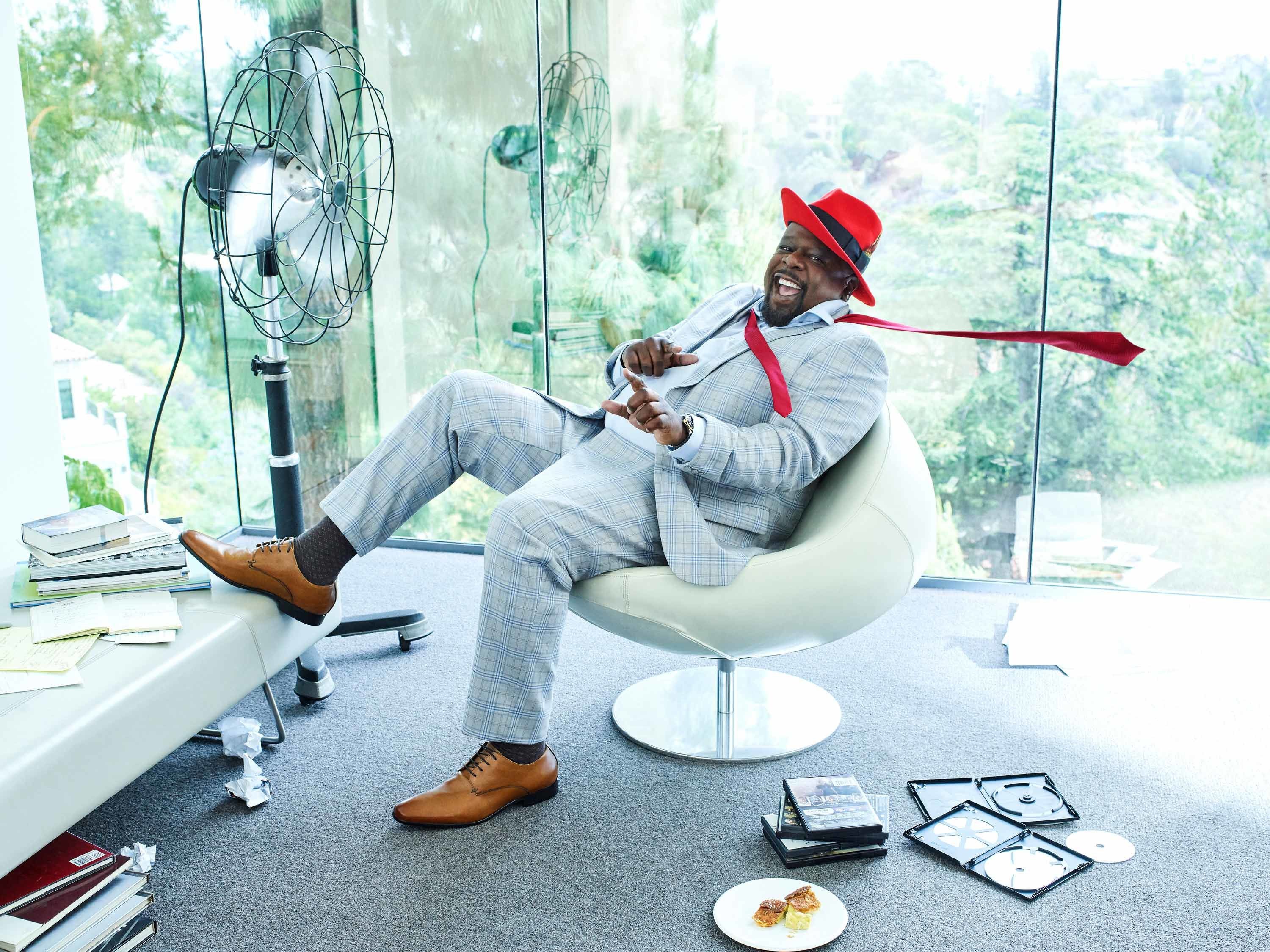 Cedric the Entertainer reclining in a chair smiling at the camera