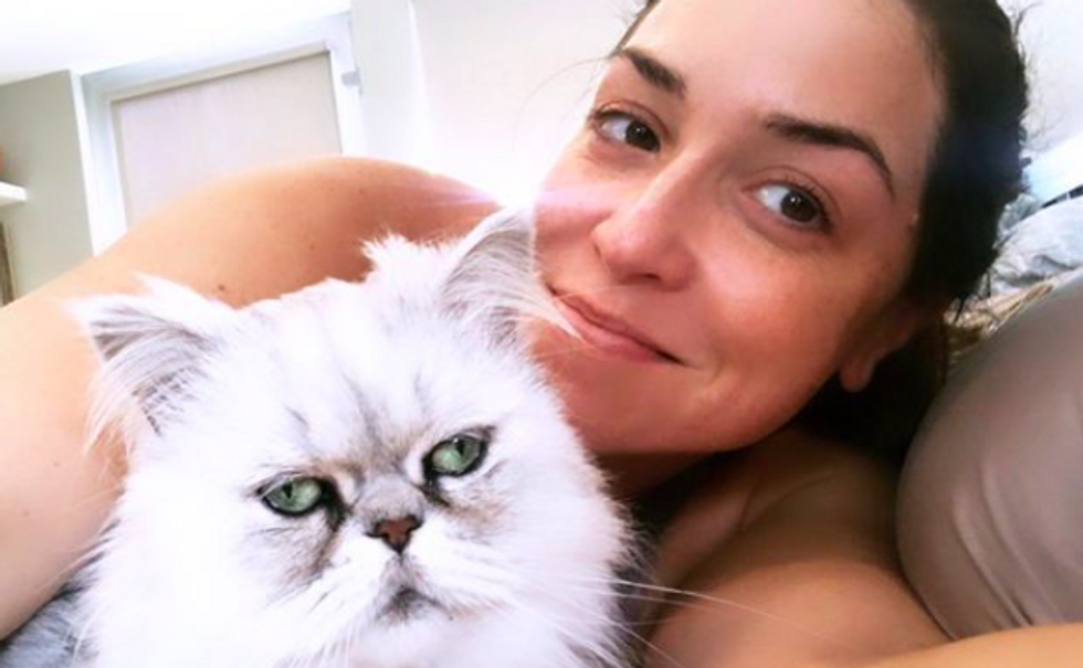 person smiling, taking selfie with their cat