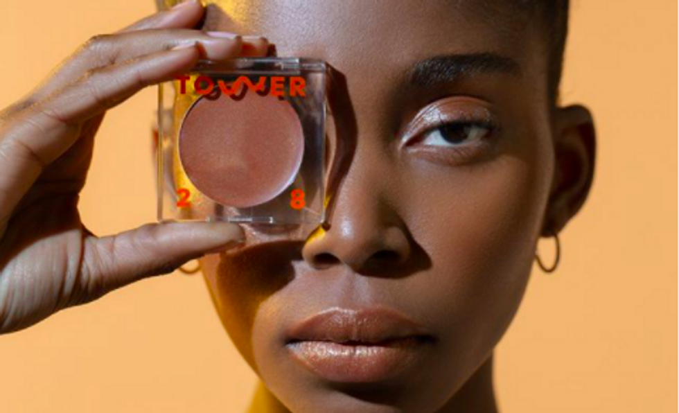 someone holding a bronzer with "tower 28" written on it over their eye