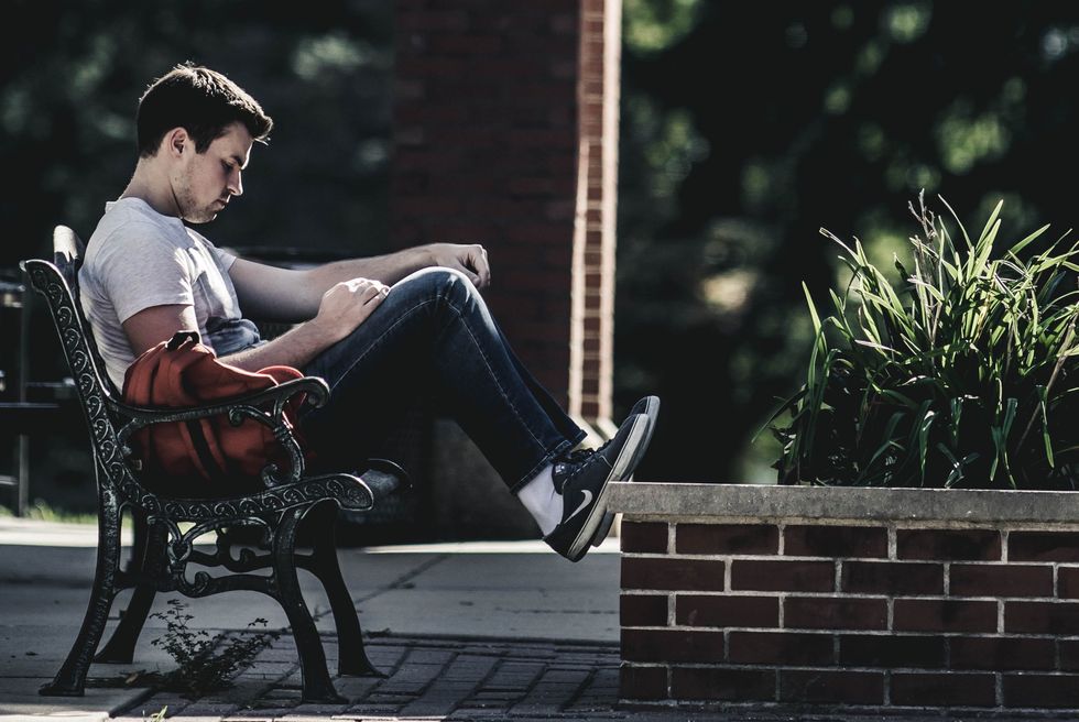 Guy sitting on bench with backpack