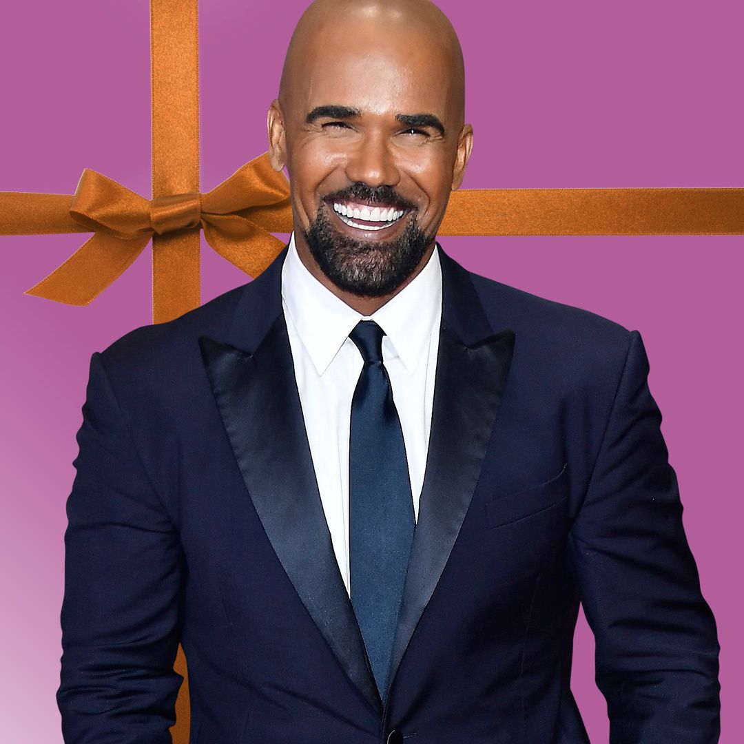 Shemar Moore in a navy blue tuxedo jacket smiles extremely broadly.