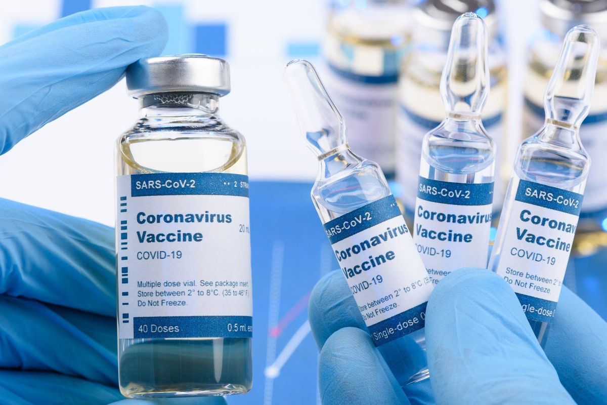 Gloved hands holding coronavirus vaccine bottles