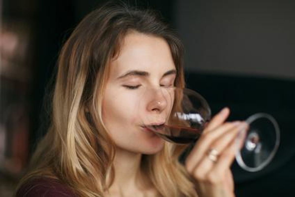 blond woman drinking glass of red wine 