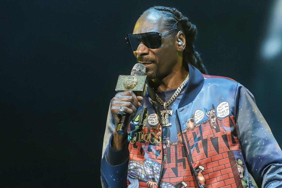 Snoop Dogg holding a mic with shades on