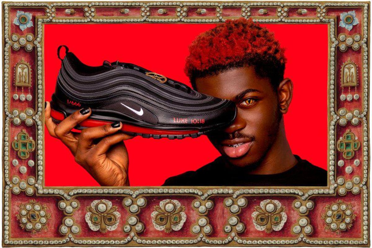 Lil Nas X holding the black Satan Shoes to his face against a red background