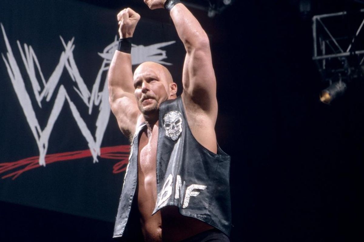 Stone Cold Steve Austin raising both arms above his head in front of the WWF logo