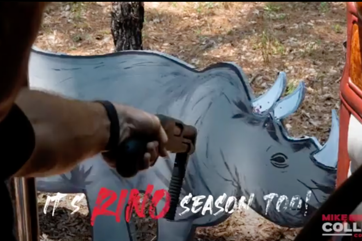 Man pointing gun at cardboard rhinoceros