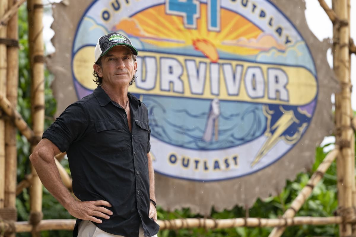 Survivor host Jeff Probst stands in front of the logo for the new season