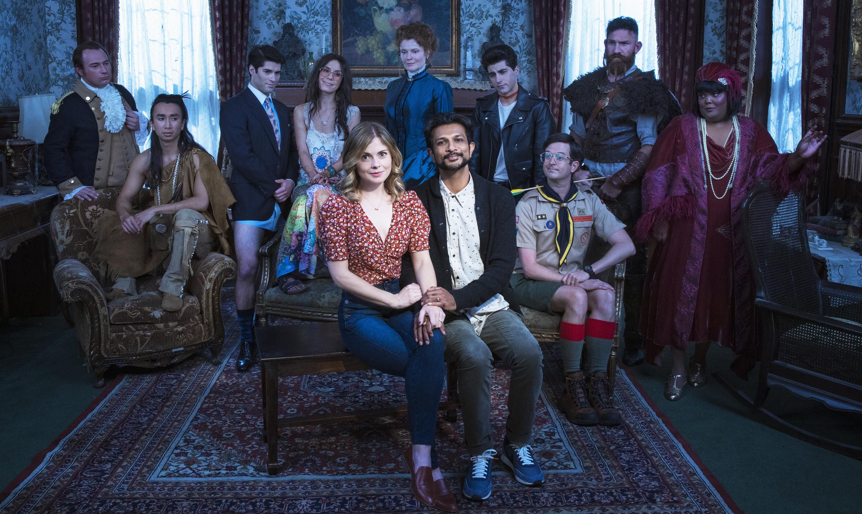 The cast of CBS's show Ghosts sits gathered in the salon of a dusty mansion.