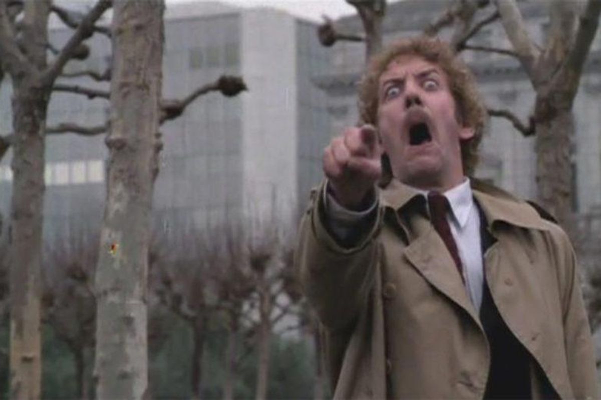 man in trenchcoat pointing in horror