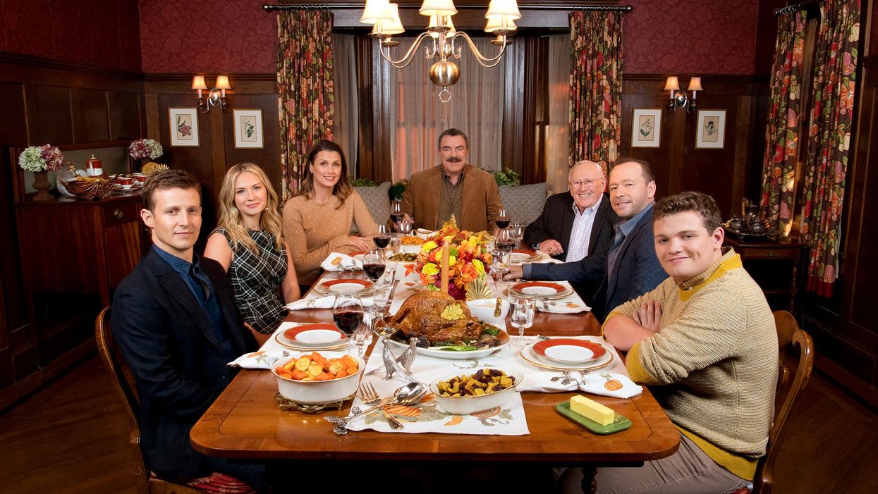 Blue Bloods cast members sit at the Reagan family table set with Thanksgiving dishes and decorations
