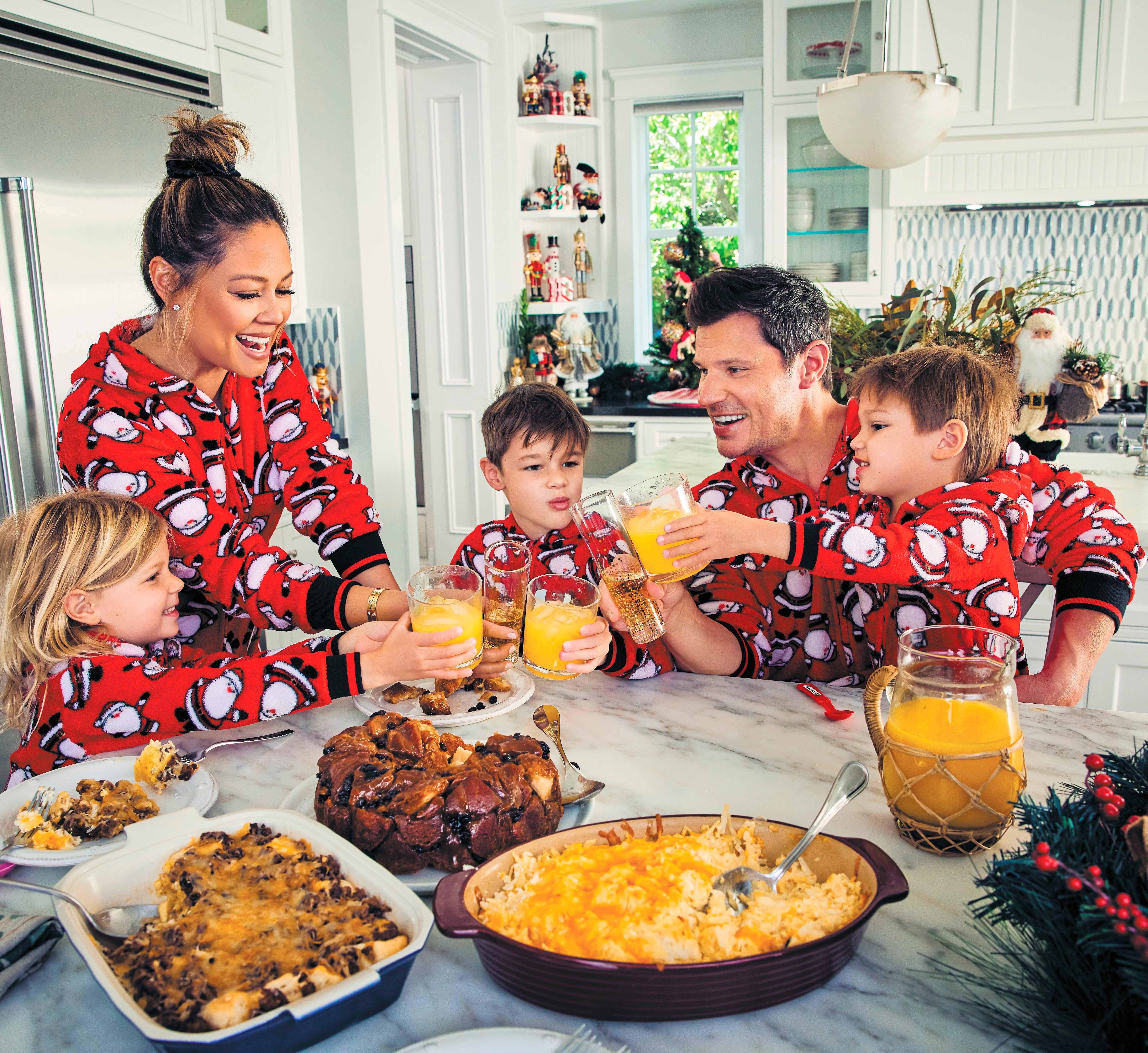 Vanessa Lachey with her three children and her husband holding cups with beverages.